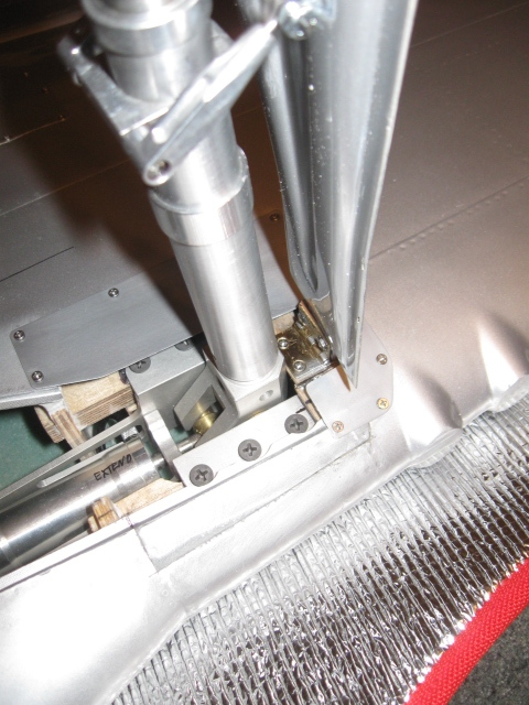 Longer shot of the outer door hinge in place against the strut base, thus parallel and in same plane, by default.